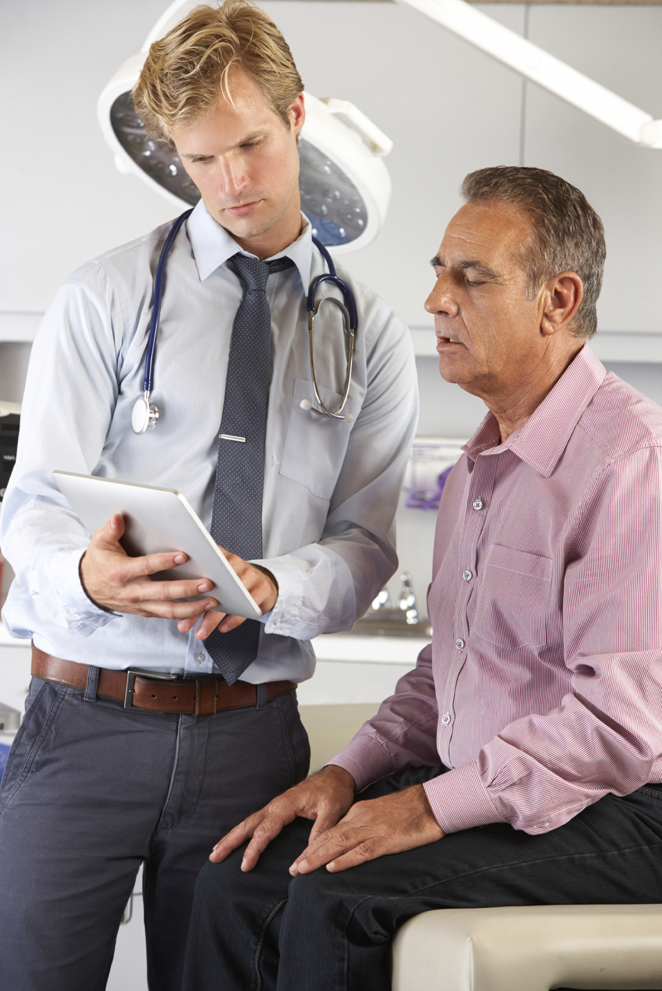 Doctor Discussing Records With Patient Using Digital Tablet